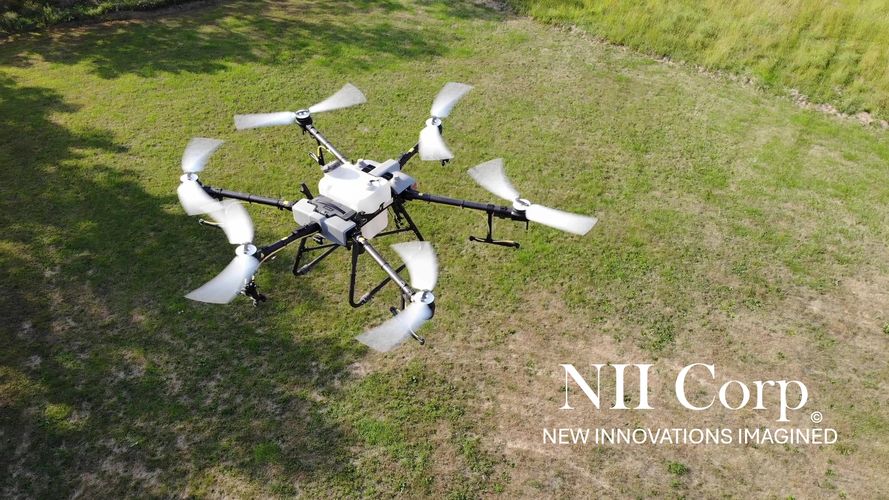 A six-rotor drone flying over a grassy field with NII Corp branding.