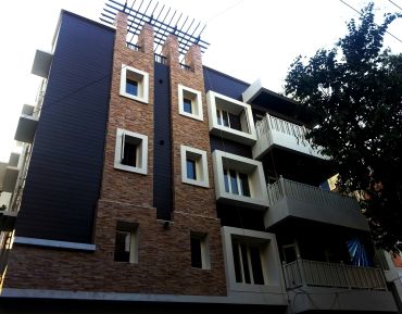 Modern building with brick and dark panels under a bright sky.