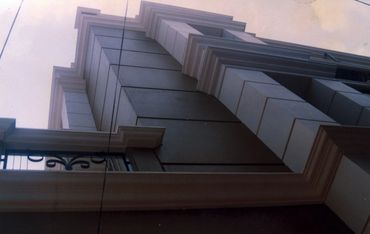 Upward view of a modern building with detailed moldings and a balcony.