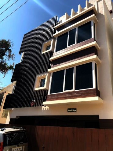 Modern residential building with sleek black and beige design elements under a clear sky.
