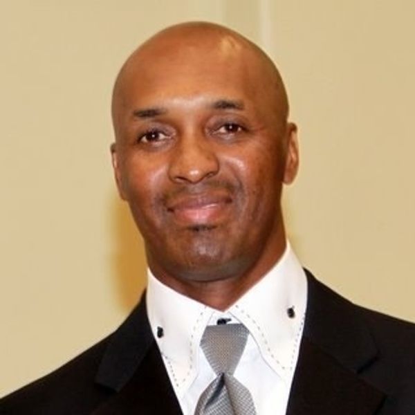 A well-dressed man in a suit and tie smiling at the camera.