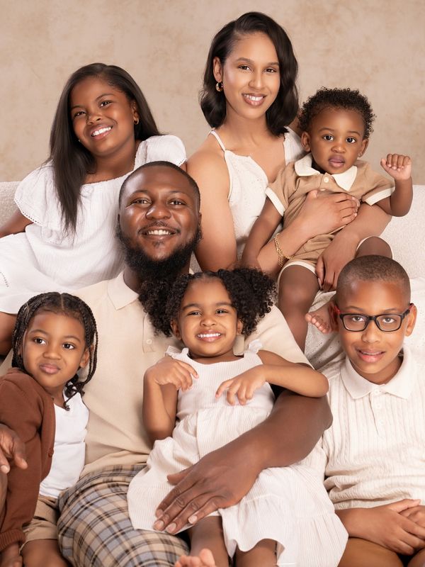 A happy family of seven posing together on a cream-colored sofa.