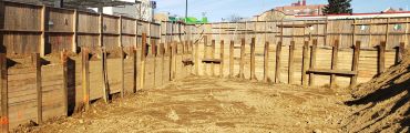 Construction site with wooden retaining walls and dirt ground.