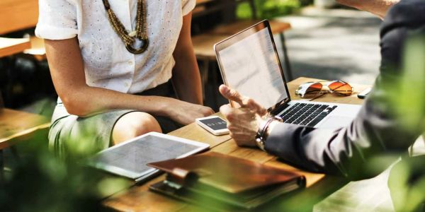 Two people discussing over a laptop at a wooden table.