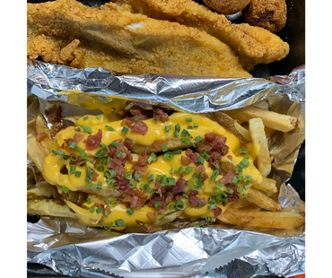 Cheese fries topped with bacon bits and chives, served with fried fish and hush puppies.