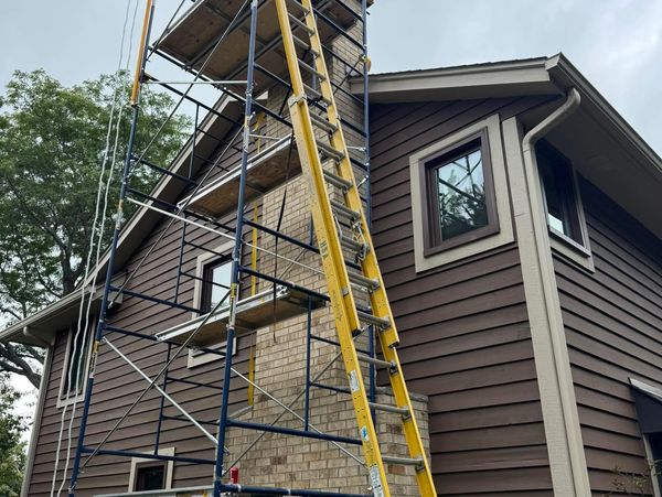 Scaffolding and ladder set up for chimney repair on a residential house.