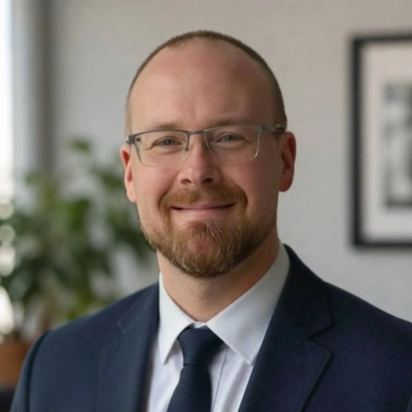 Smiling man in glasses and suit.