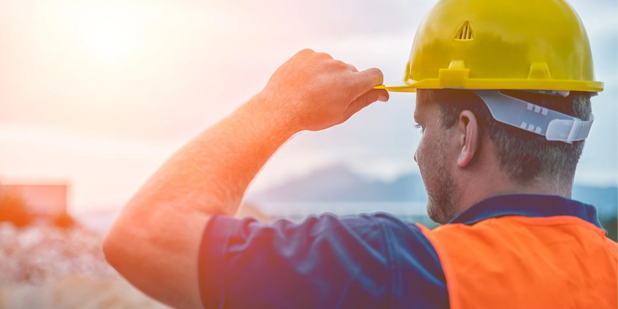 Construction worker adjusting his yellow helmet outdoors.