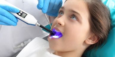 A child undergoing dental treatment with a curing light.