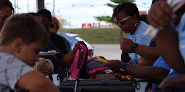 People gathered outdoors, engaging in an activity with backpacks and supplies.