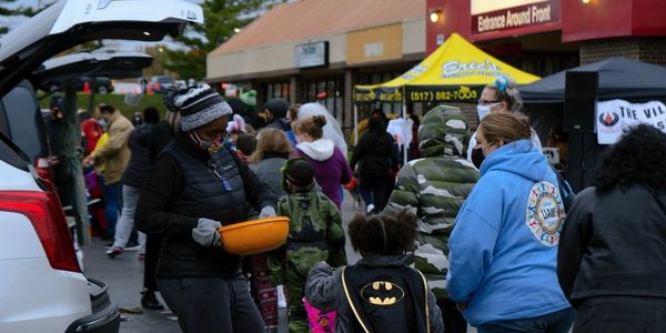 People gather outdoors for a community event with food distribution and socializing.