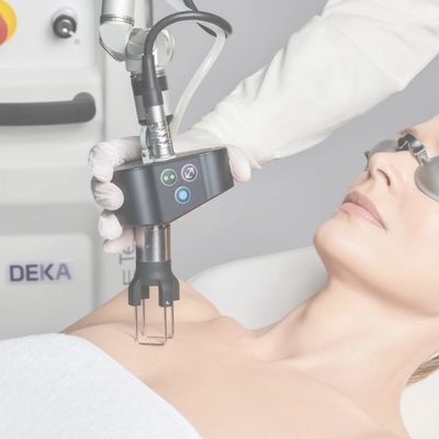 A woman undergoes a laser skin treatment on her chest while wearing protective goggles.