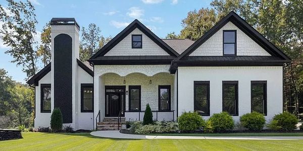 Modern white two-story house with black trim and well-maintained lawn.
