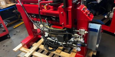 Red industrial machine with cables on a wooden pallet.