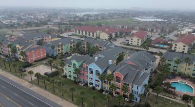 Colorful apartment buildings near a road with palm trees.