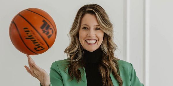 Woman smiling while spinning a basketball on her finger.