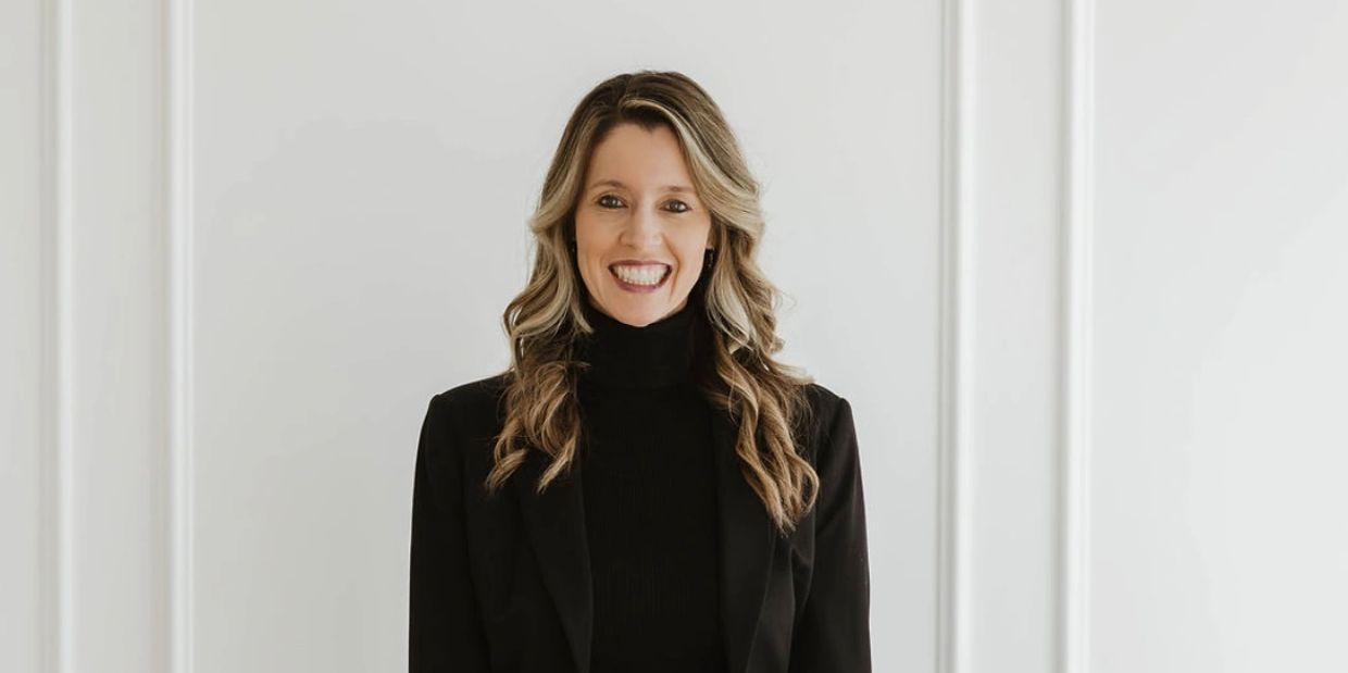 Woman in a black suit smiling.