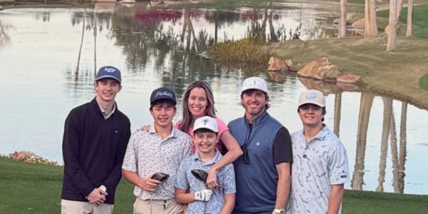 Group of six people posing by a golf course water feature.