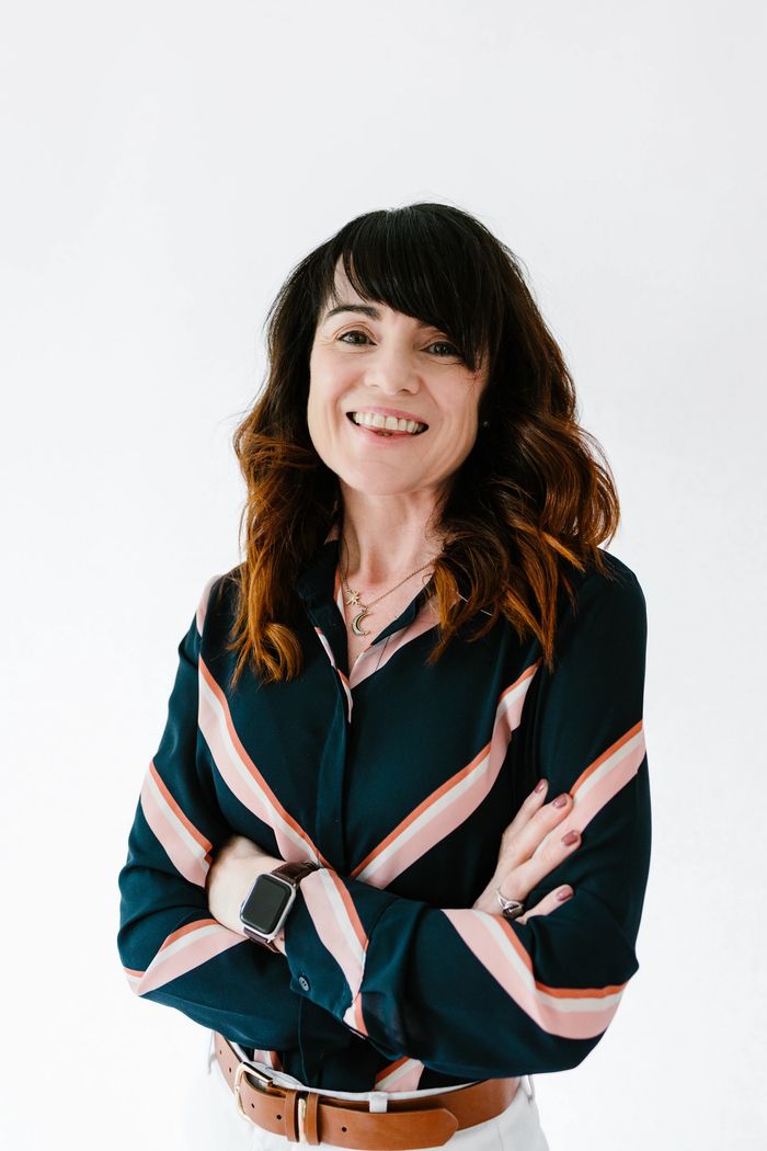 Prof Maura McAdam- is standing with arms folded and smiling