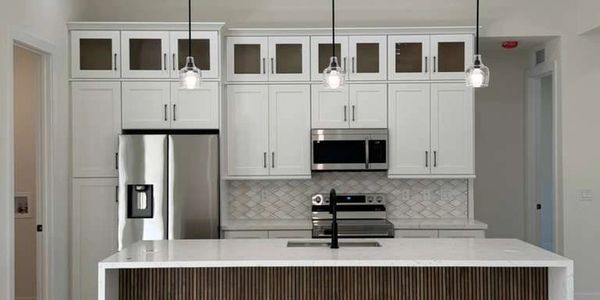 Modern kitchen with white cabinets, stainless steel appliances, and a wooden island.
