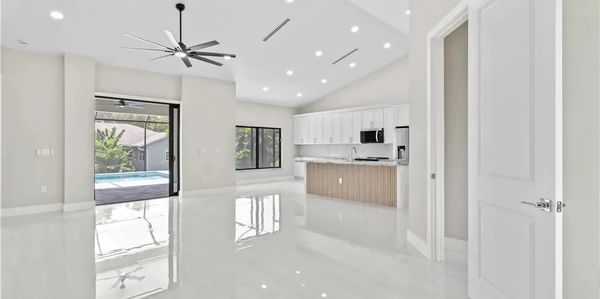 Modern open-plan kitchen and living area with glossy floor and ceiling fan.