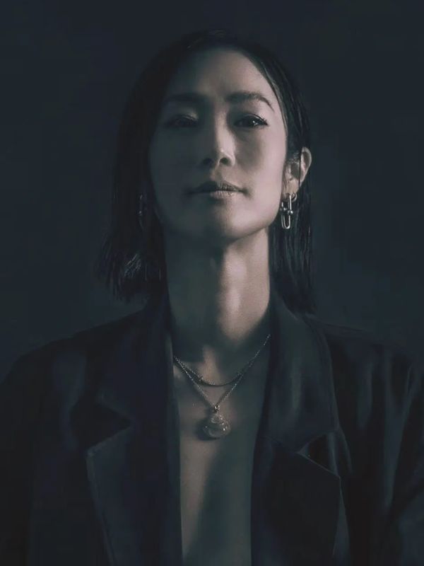 Moody portrait of a woman with dark blazer and jewelry.