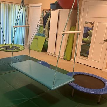 This is a colorful sensory playroom with blue and green sensory hanging over green floor mats.