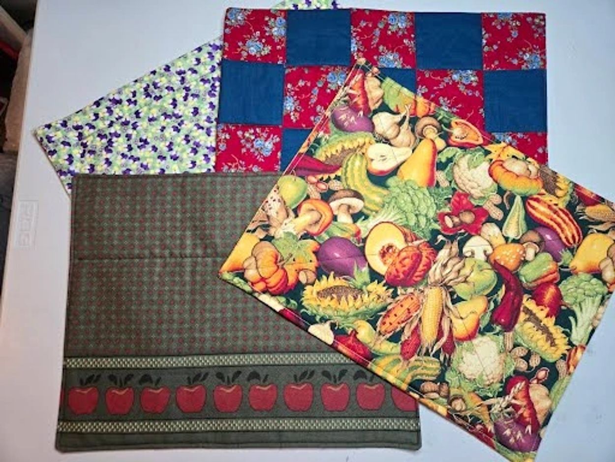 Colorful fabric squares with fruit and vegetable patterns on a white table.