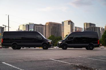 Two black vans facing each other against a city skyline.