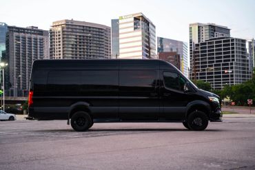Black cargo van parked in an urban area at dusk.