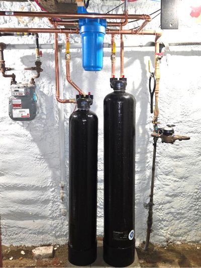 Two black water filtration tanks installed with copper piping.