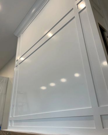 Glossy white paneled wall with recessed lighting reflections.