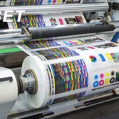 A large printing press producing color test sheets on a roll of paper.