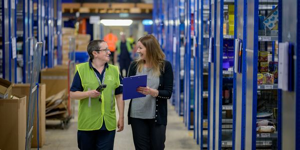 Two people reviewing inventory in a warehouse, promoting efficient material handling and control.