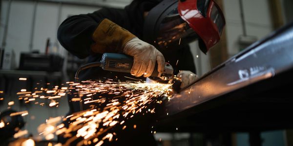 Worker in Norfolk manufacturing using a grinder, showcasing business efficiency improvements.