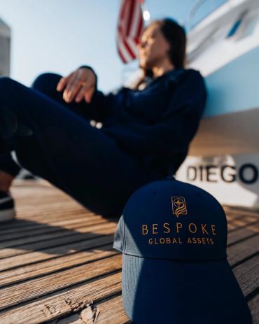 A cap with Bespoke Global Assets logo on a dock.