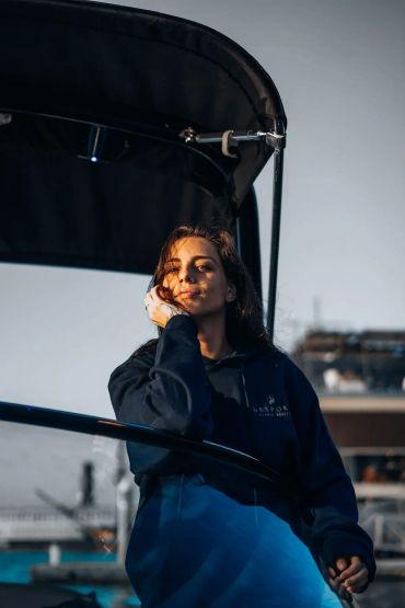 Woman resting on a boat wearing a hoodie.