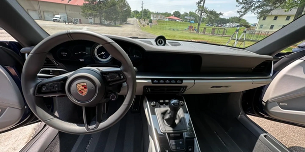 Interior of a Porsche car with manual transmission and two open doors.