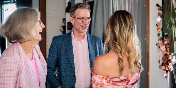 Three people engaged in a cheerful conversation indoors.