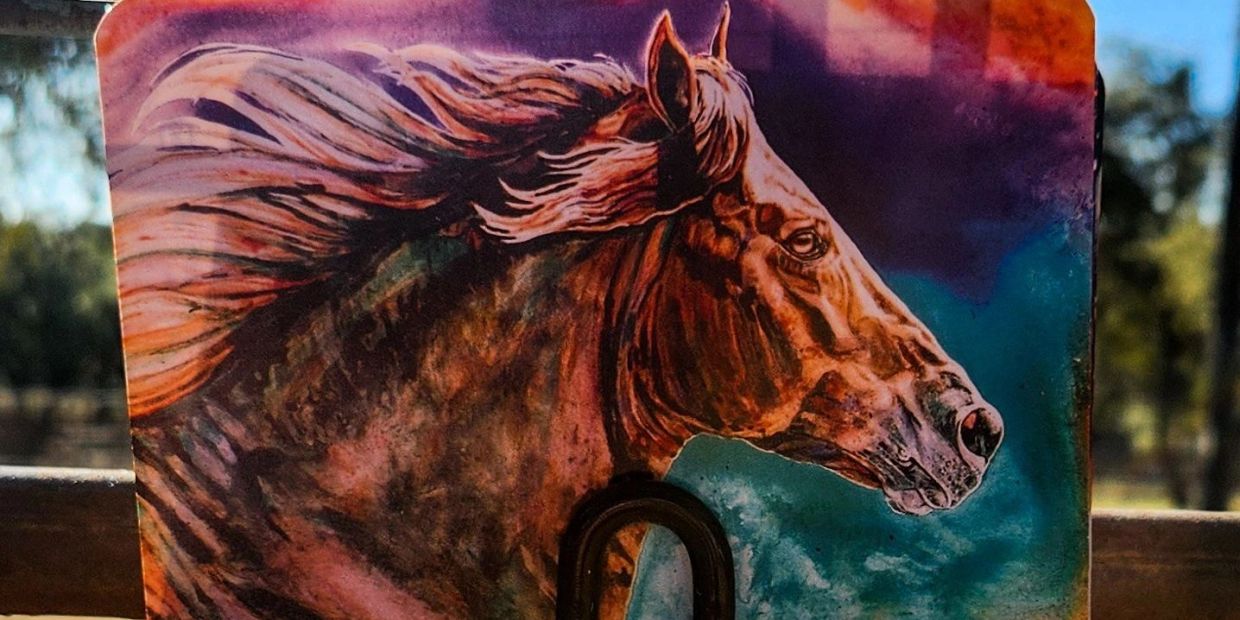 Artistic horse portrait attached to a metal fence.