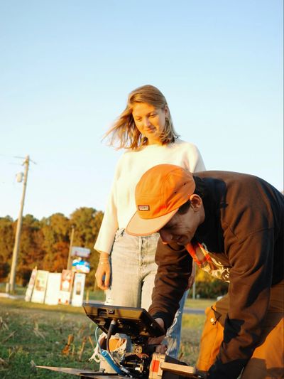 Celia Aniskovich, Director, a woman standing outdoors, beside a camera man with a large camera.