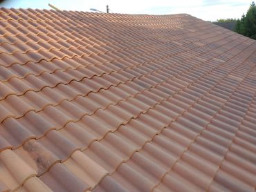 A terracotta tiled roof under clear sky.