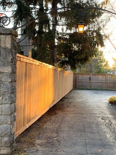 custom cedar cap and trim privacy fence installed along a driveway