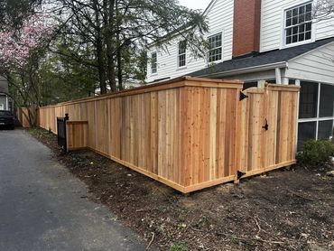 A custom cedar cap and trim wood fence with a arched gate