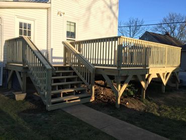 custom treated deck with a treated handrail and steps with angle bracing