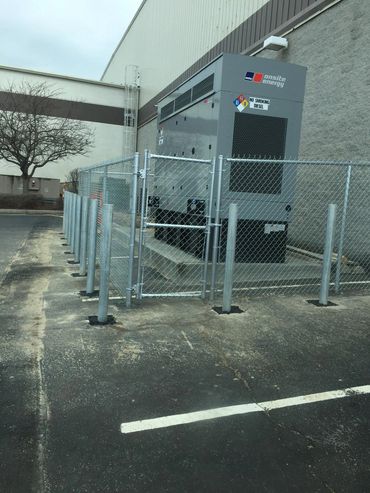 Large industrial generator enclosure with chainlink fence and bollard posts