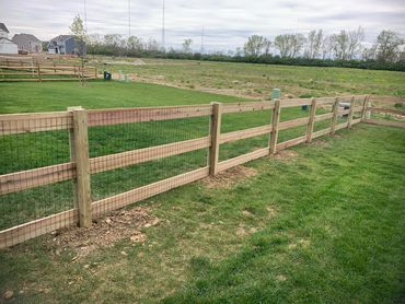 poplar three board wood fence with wire mesh enclosing a backyard.