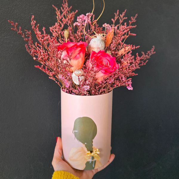 Light pink box adorned with a silhouette of a person, holding a bouquet of roses, and foliage