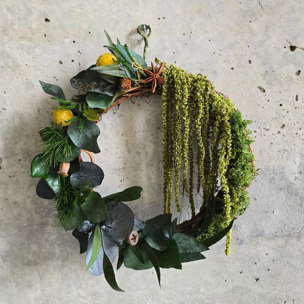 A wreath decorated with green preserved moss and plants.