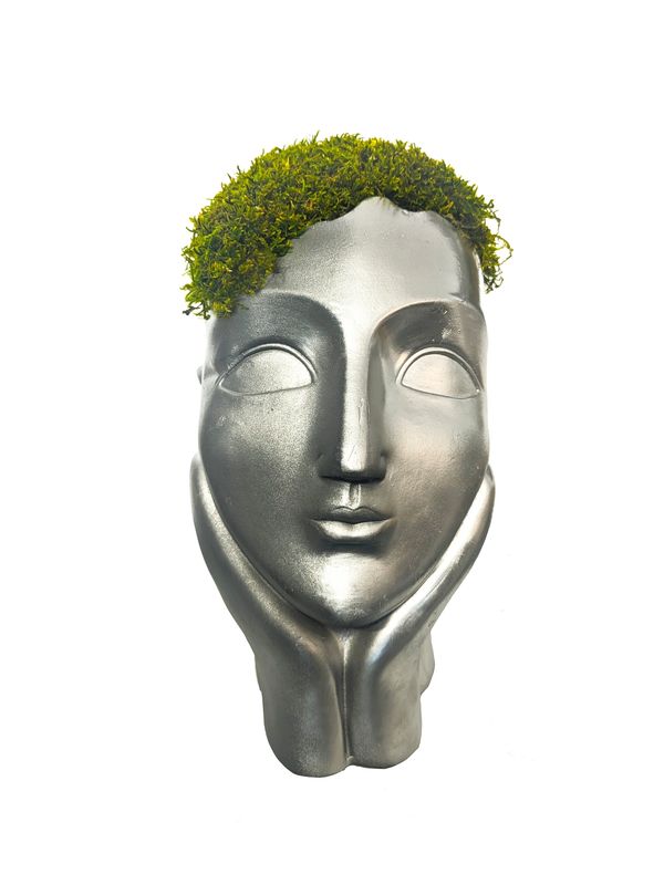 Shiny silver planter shaped human face, with hands cupping the chin, is adorned with moss.